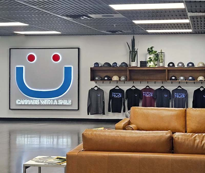 Inside Frosted Nug NJ Dispensary with Couches and a Large Smiling Sign